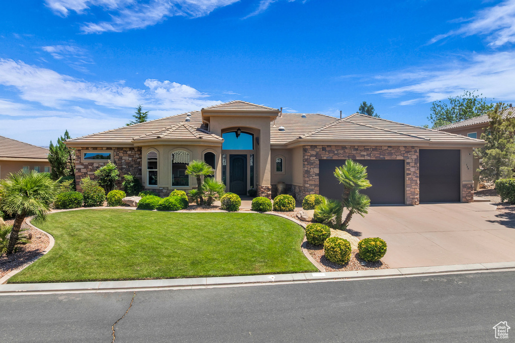 Mediterranean / spanish-style house with stone siding, a garage, a tile roof, concrete driveway, and stucco siding