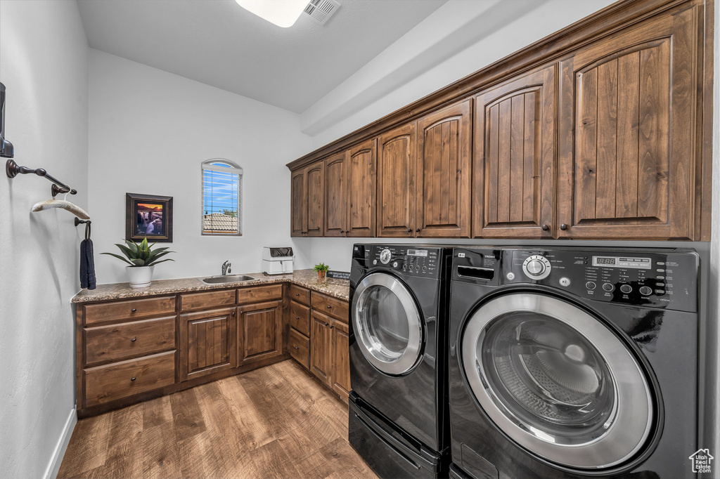 Laundry room with cabinet space, independent washer and dryer, and wood finished floors