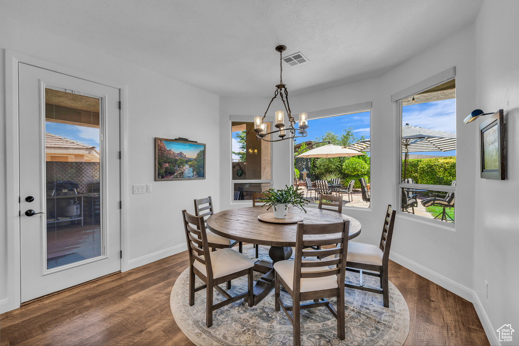 Dining area with a chandelier and dark wood-type flooring