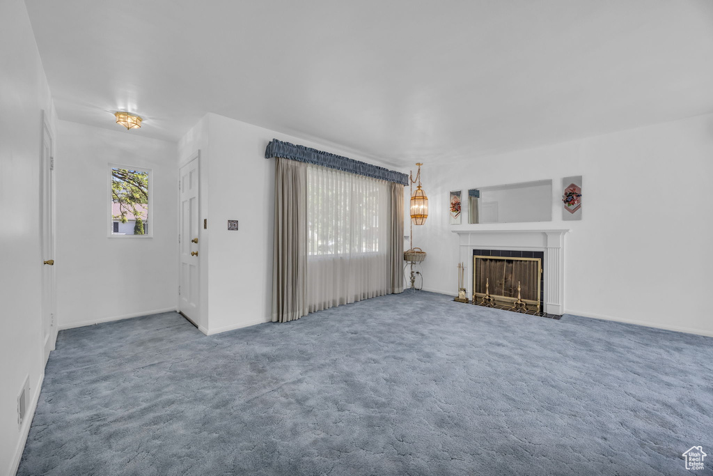 Unfurnished living room featuring carpet and a fireplace with flush hearth