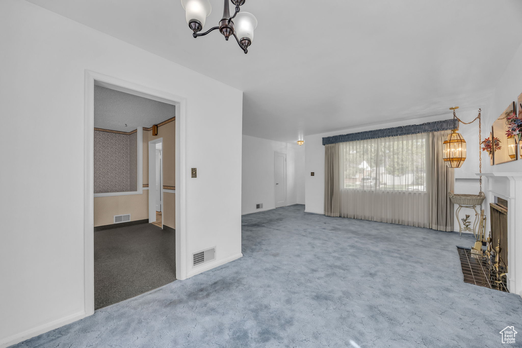 Unfurnished living room with a chandelier, carpet flooring, and a fireplace