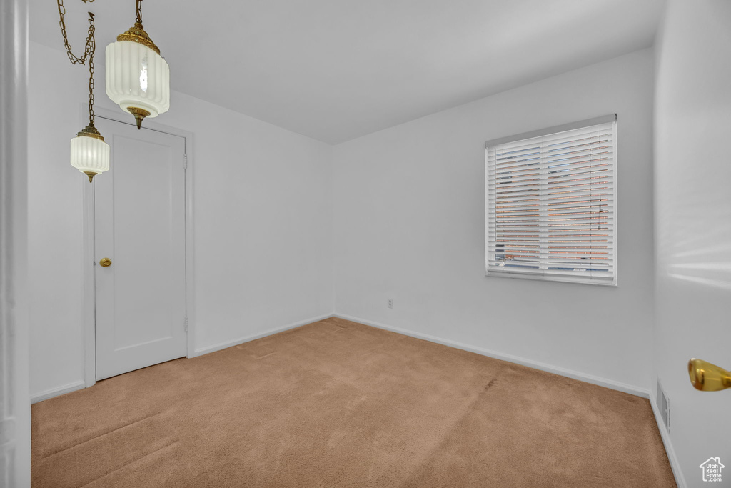 Carpeted spare room featuring baseboards