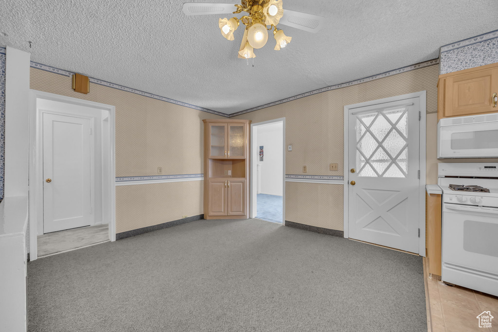 Kitchen featuring white appliances, wallpapered walls, ceiling fan, a textured ceiling, and light colored carpet