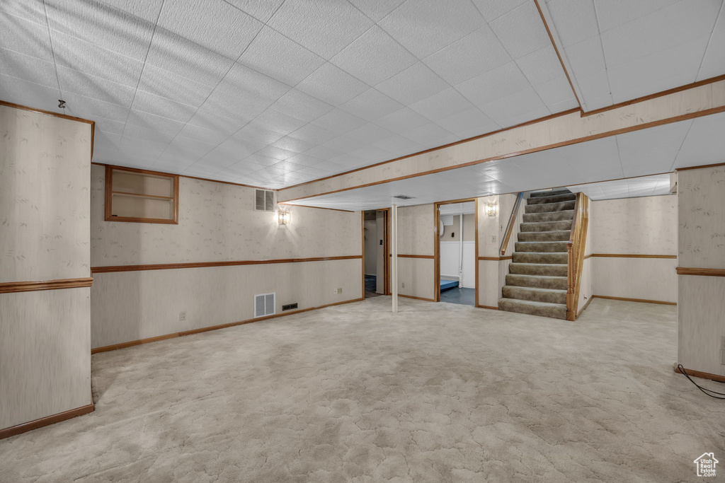 Finished below grade area featuring stairway, carpet flooring, wallpapered walls, and a wainscoted wall