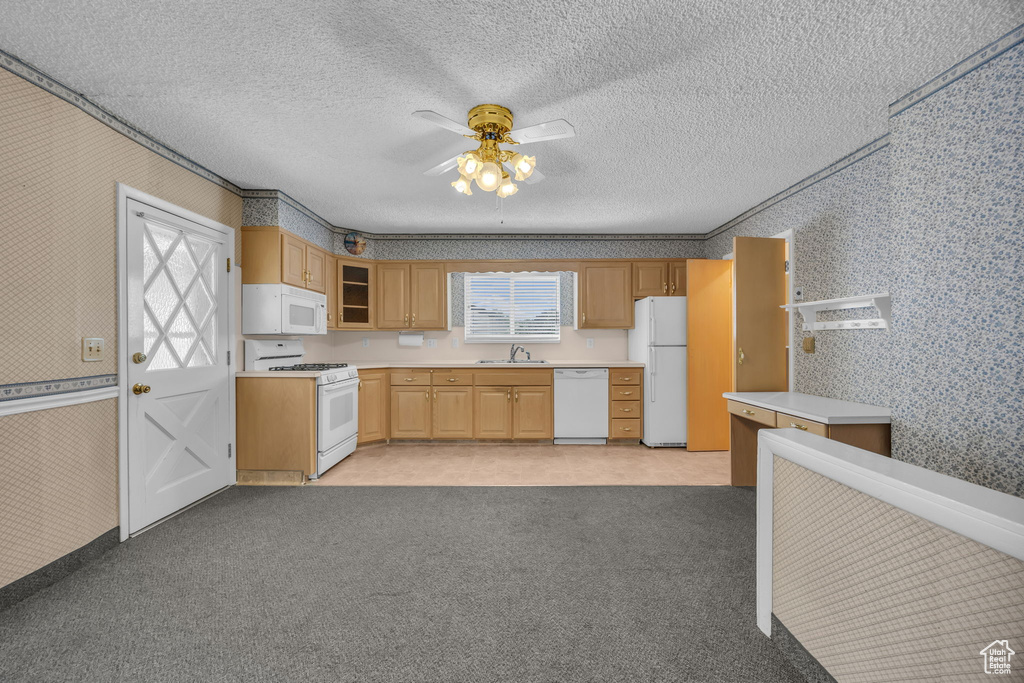Kitchen with white appliances, wallpapered walls, a ceiling fan, light countertops, and light colored carpet