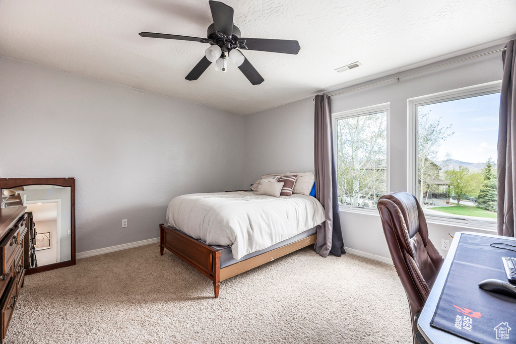 Bedroom with light carpet, a ceiling fan, and an office area