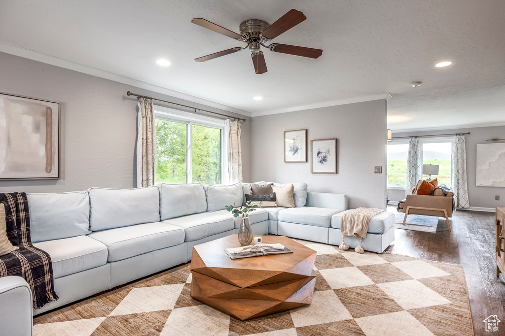 Living room with plenty of natural light, wood finished floors, ceiling fan, crown molding, and recessed lighting