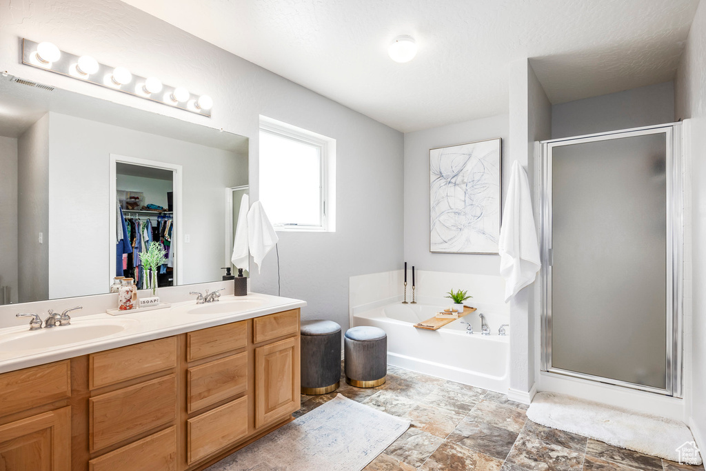 Full bath with a shower stall, a garden tub, double vanity, and a walk in closet