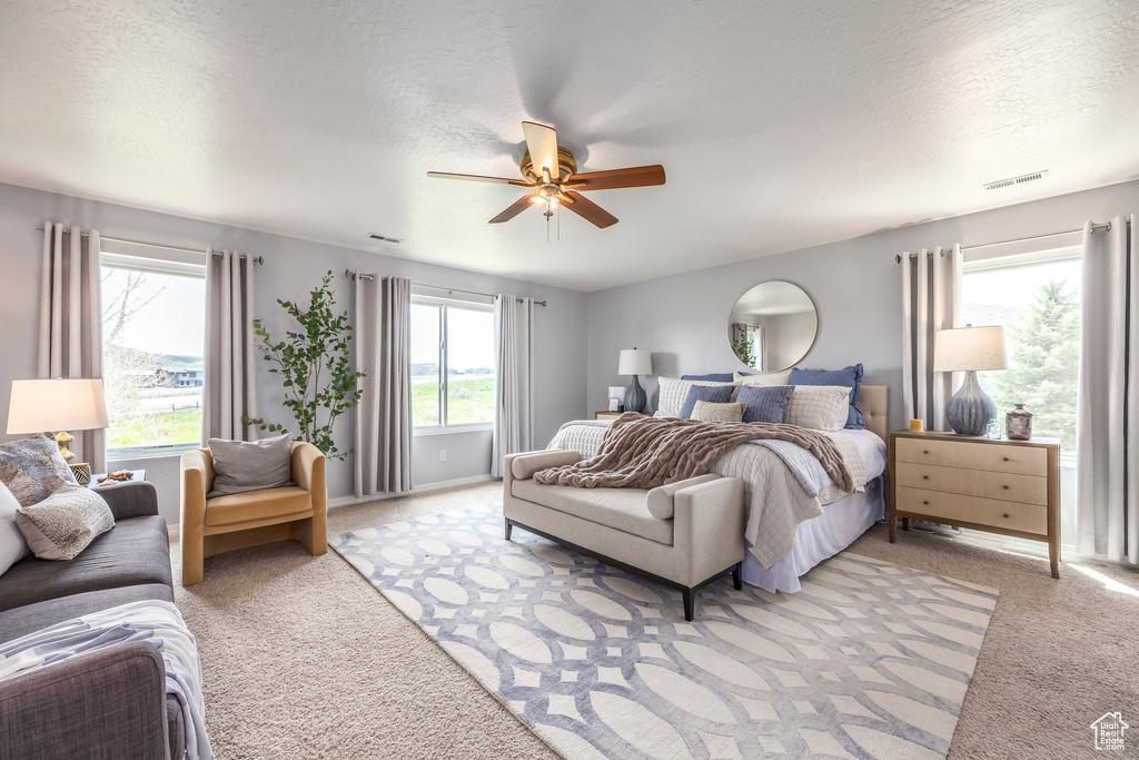 Bedroom with light carpet, a ceiling fan, and a textured ceiling