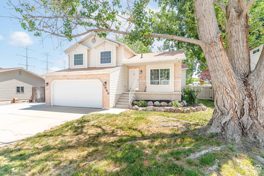 Tri-level home featuring brick siding, an attached garage, and concrete driveway