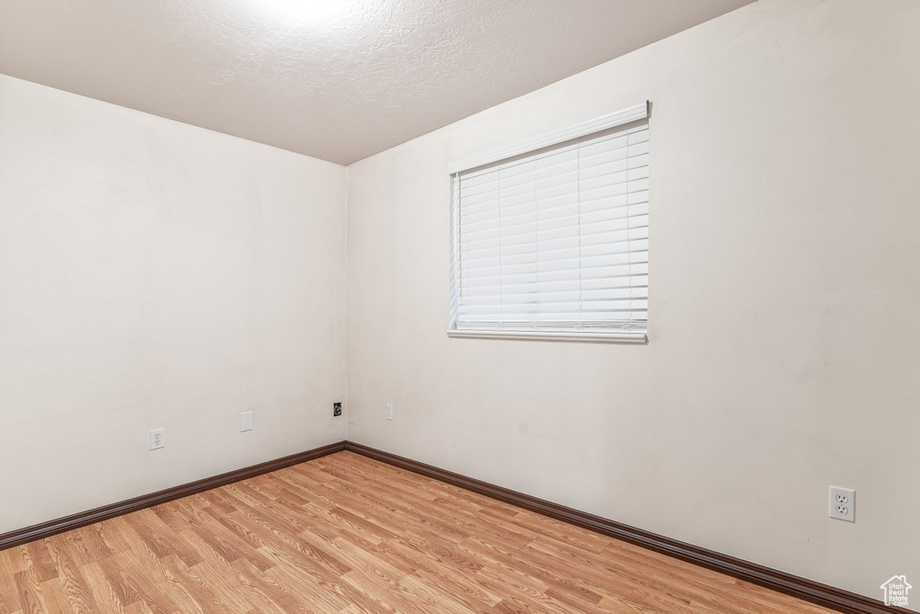 Unfurnished room featuring light wood finished floors and a textured ceiling