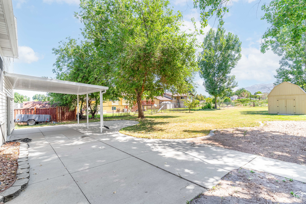 Fenced backyard with a shed, a patio area, and a carport