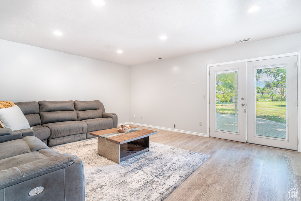 Living room with light wood-type flooring and recessed lighting