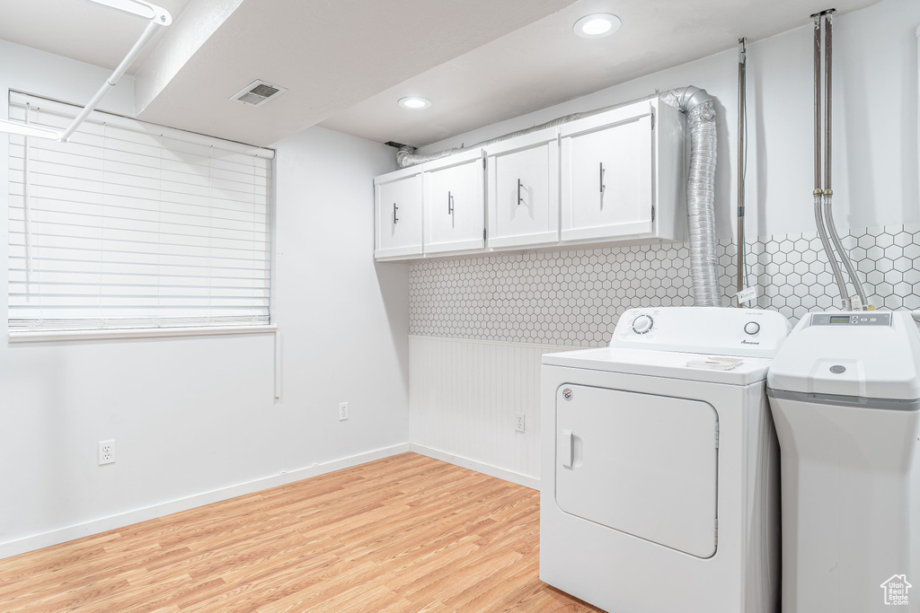 Washroom with washer and dryer, cabinet space, light wood finished floors, and recessed lighting