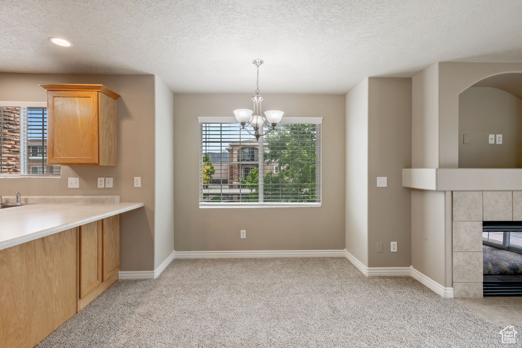 Kitchen featuring a chandelier, light carpet, a textured ceiling, light countertops, and a tile fireplace