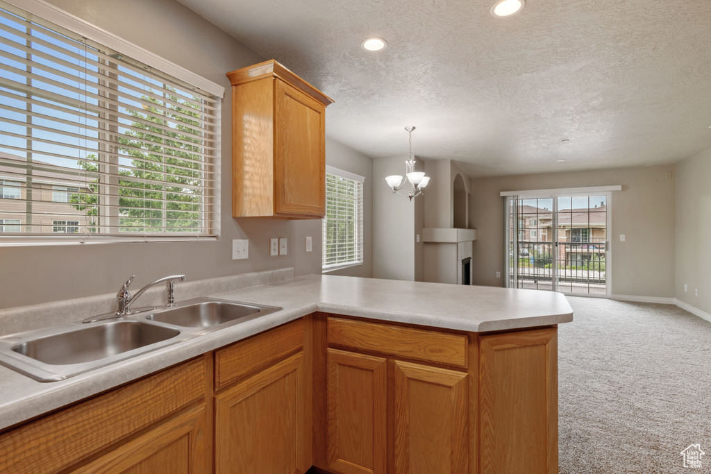 Kitchen with a peninsula, light countertops, light colored carpet, a textured ceiling, and open floor plan