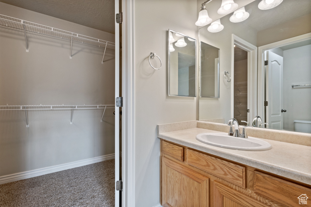 Full bath featuring vanity and a walk in closet