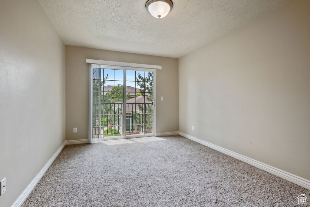 Carpeted empty room featuring a textured ceiling and baseboards