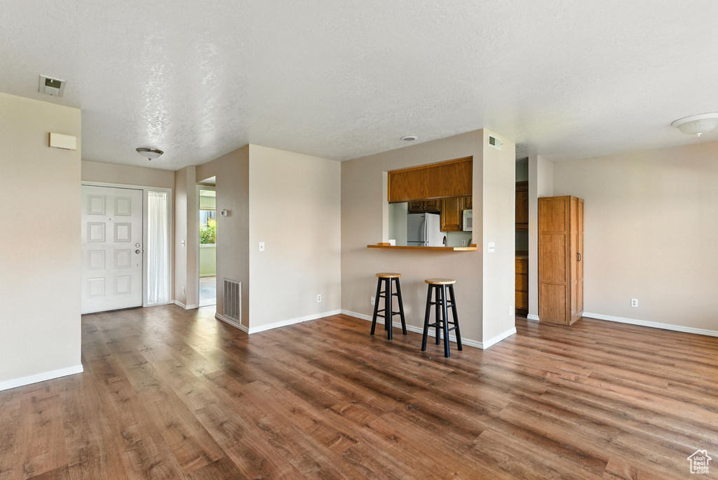 Unfurnished living room featuring wood finished floors and a textured ceiling