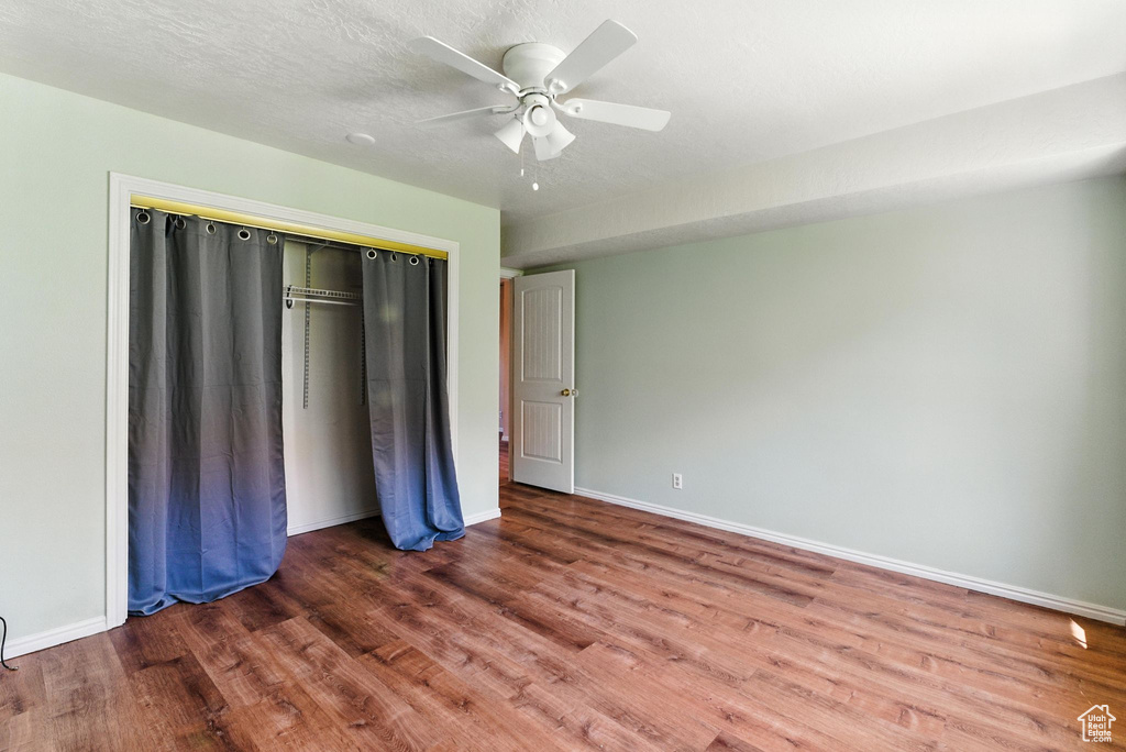 Unfurnished bedroom featuring wood finished floors, a closet, and a ceiling fan