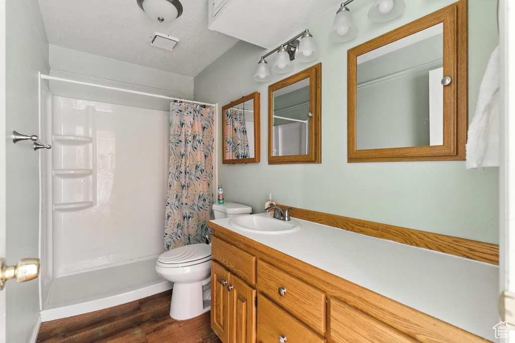 Full bath featuring vanity, wood finished floors, and shower / tub combo with curtain