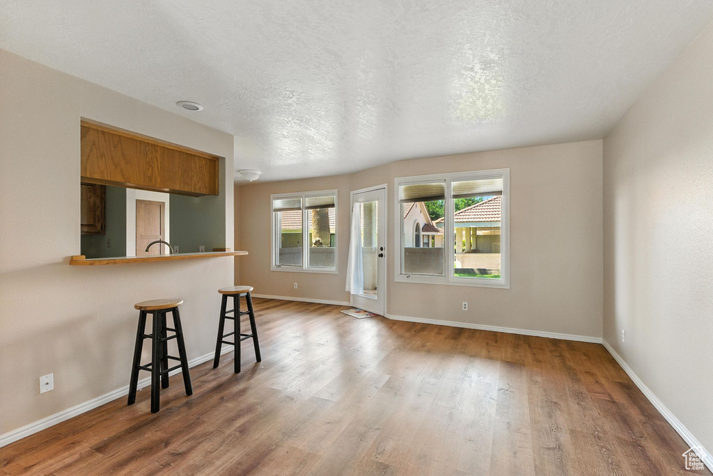 Kitchen featuring a breakfast bar area, brown cabinetry, wood finished floors, a peninsula, and a textured ceiling