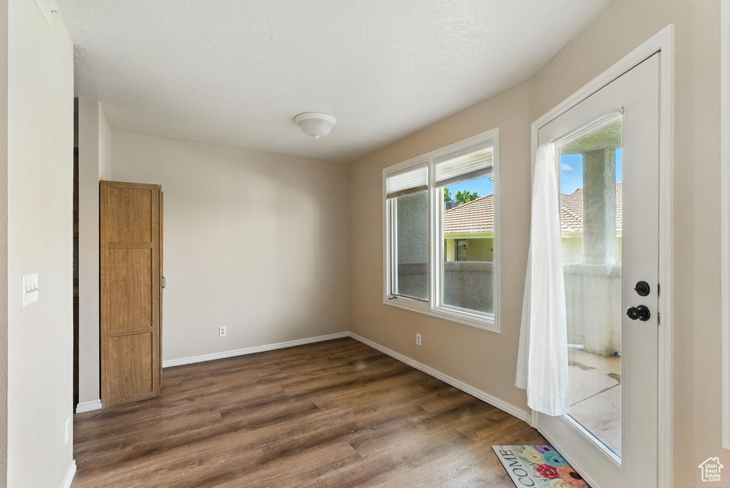 Empty room featuring dark wood-style flooring and baseboards