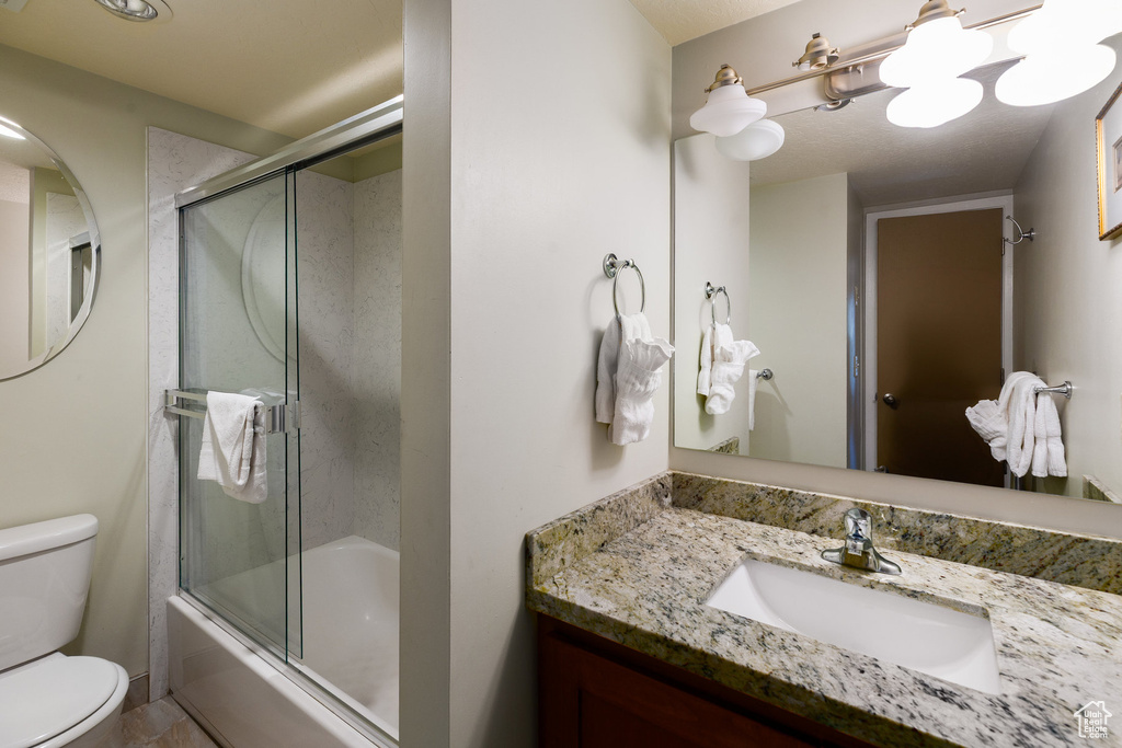 Bathroom with vanity and bath / shower combo with glass door