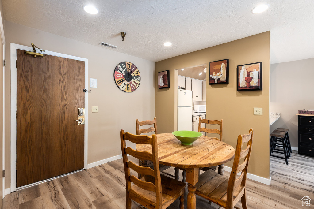 Dining space with light wood-style flooring, recessed lighting, and a textured ceiling