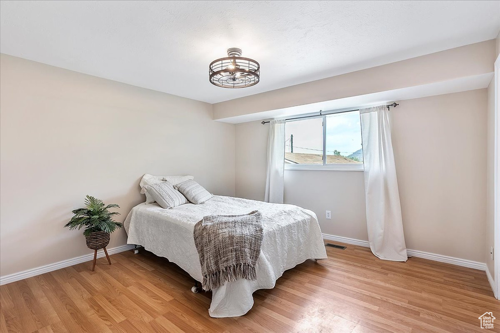 Bedroom with light wood-type flooring and a chandelier