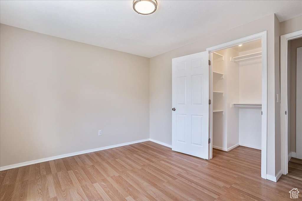 Unfurnished bedroom featuring light wood-style flooring, a spacious closet, and a closet