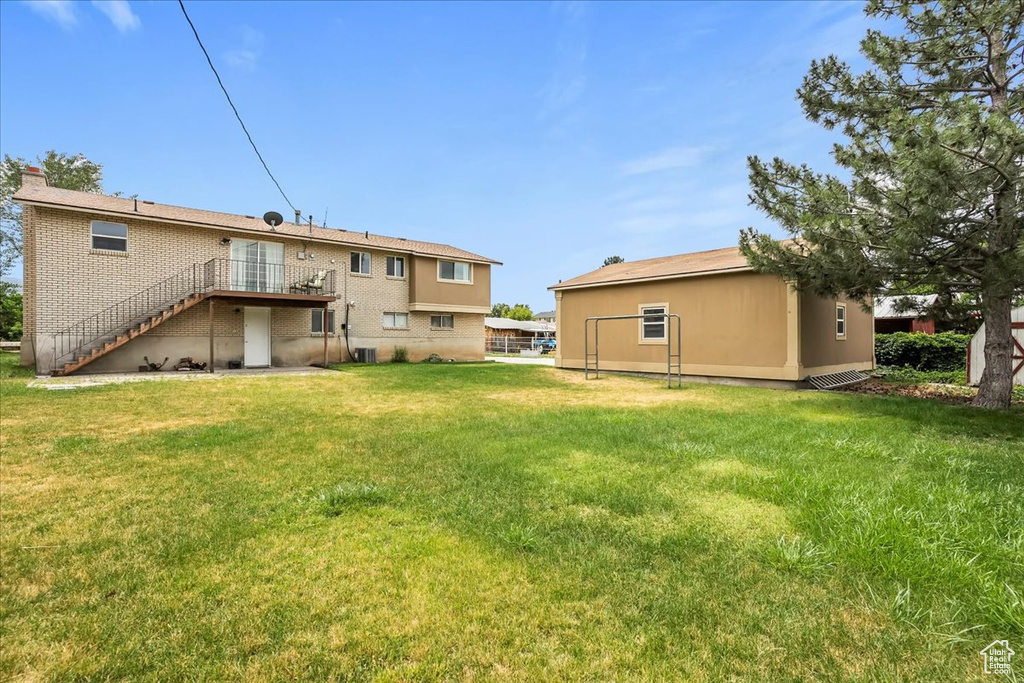 Back of property with stairs, a yard, a deck, and brick siding
