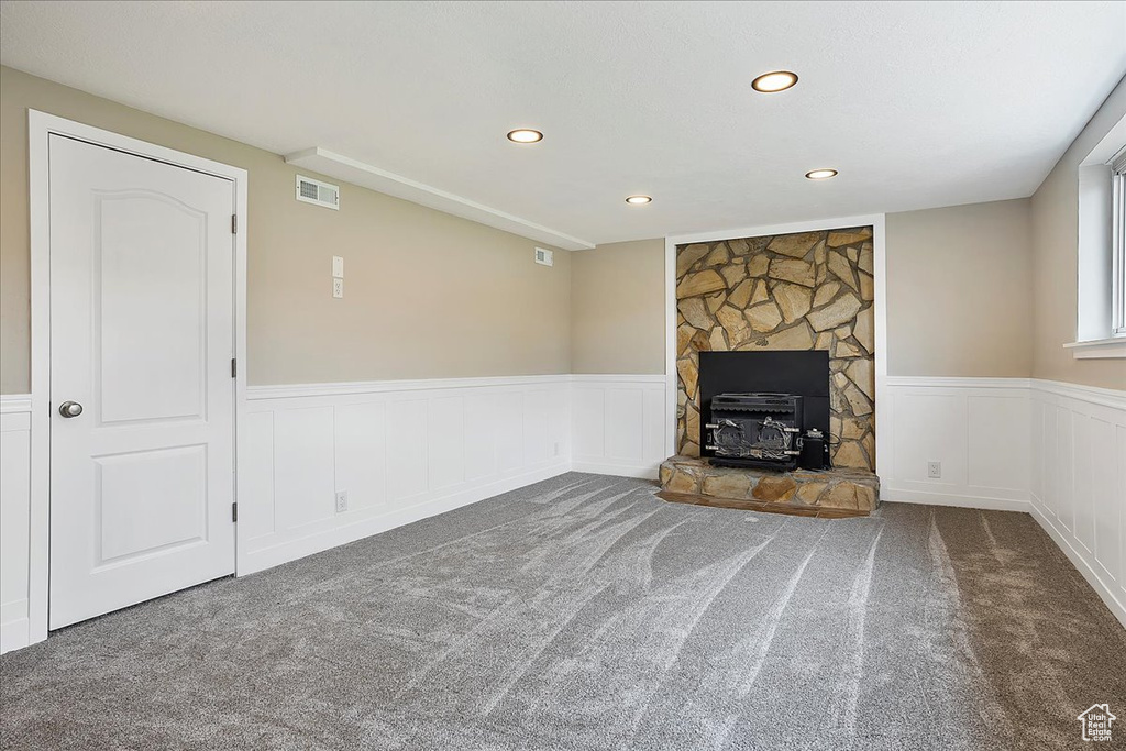 Unfurnished living room featuring carpet flooring, wainscoting, recessed lighting, and a decorative wall