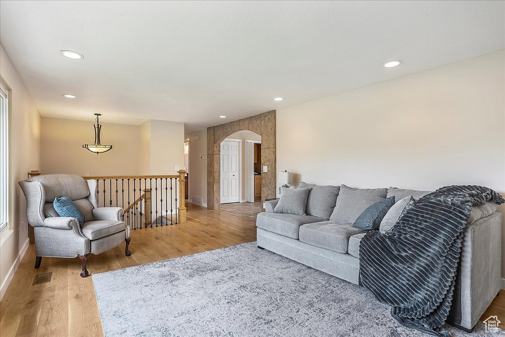 Living area with light wood-type flooring, arched walkways, and recessed lighting