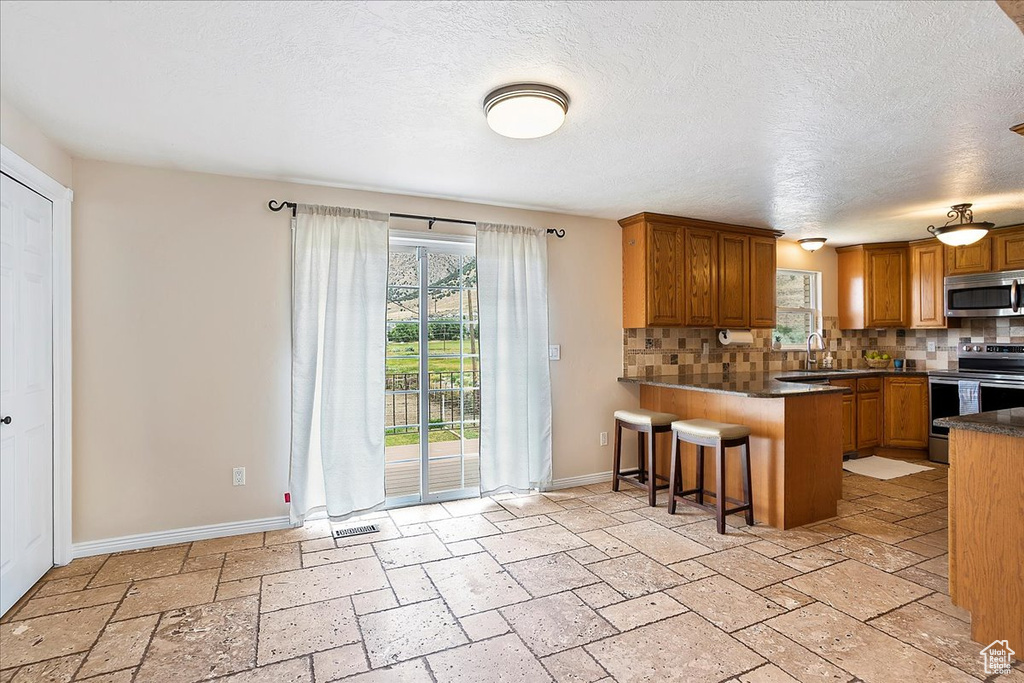 Kitchen with appliances with stainless steel finishes, tasteful backsplash, healthy amount of natural light, and a textured ceiling