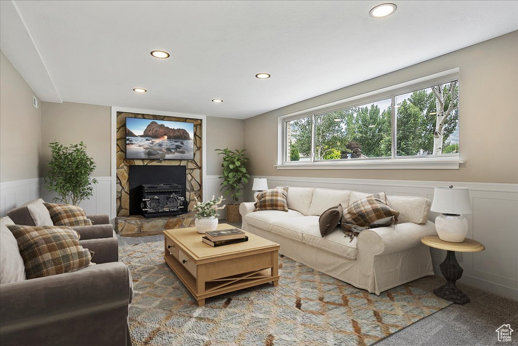 Carpeted living area featuring wainscoting, recessed lighting, and a stone fireplace
