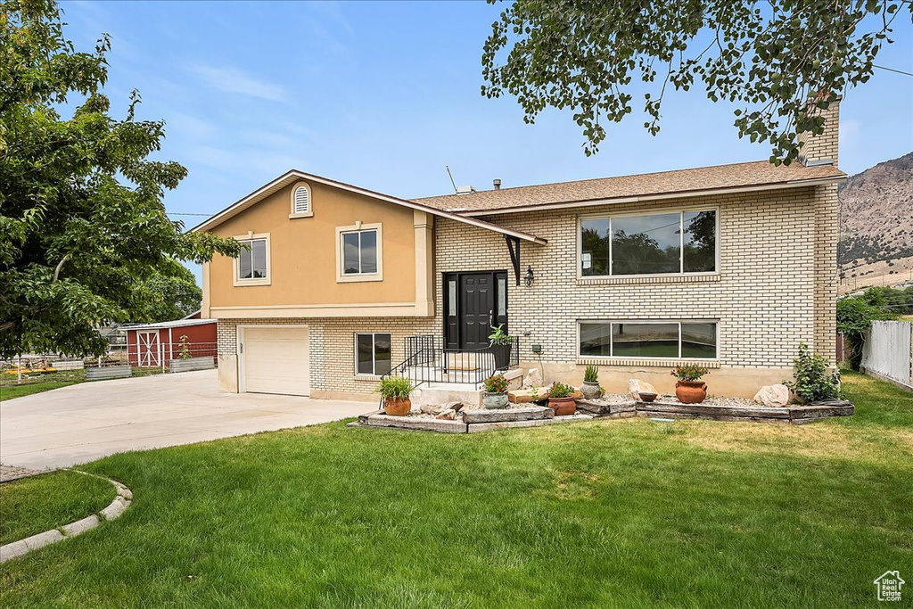 Split foyer home featuring driveway, a garage, and brick siding