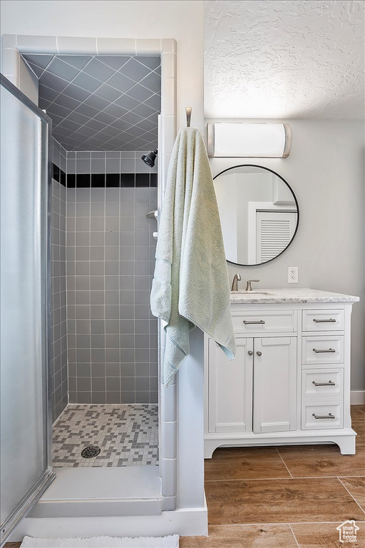 Full bathroom with a shower stall, vanity, and wood finished floors