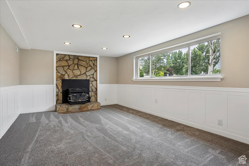 Unfurnished living room featuring recessed lighting, a wainscoted wall, carpet flooring, a decorative wall, and a fireplace