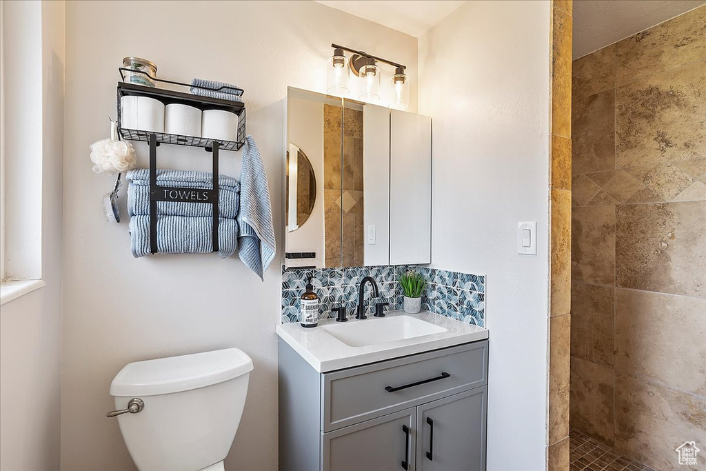 Bathroom with vanity, a tile shower, and decorative backsplash