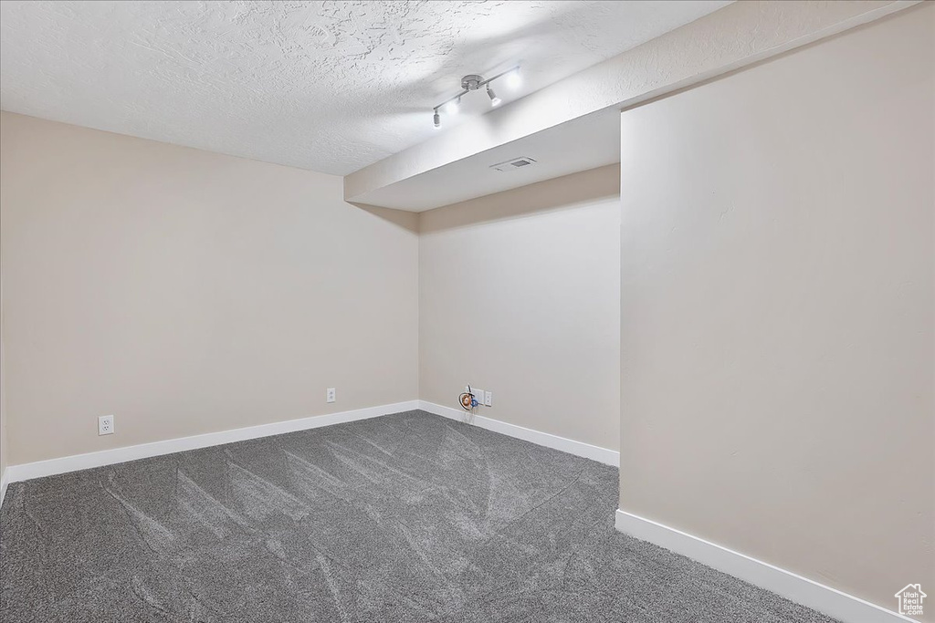 Finished below grade area featuring dark colored carpet and a textured ceiling