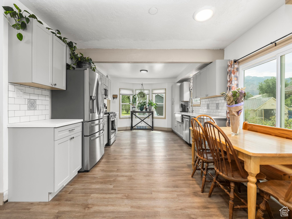 Kitchen with appliances with stainless steel finishes, light countertops, light wood-style floors, and decorative backsplash