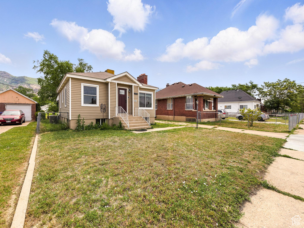 Bungalow-style home with a chimney, a detached garage, concrete driveway, and a mountain view
