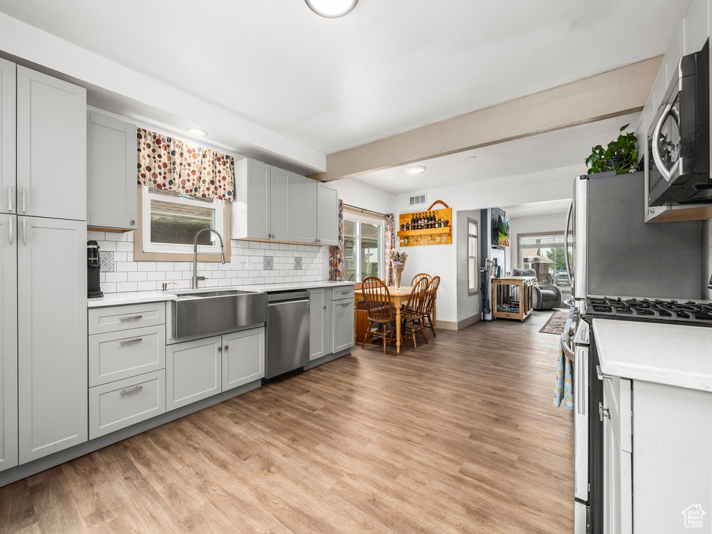 Kitchen featuring appliances with stainless steel finishes, light countertops, decorative backsplash, light wood-style floors, and recessed lighting