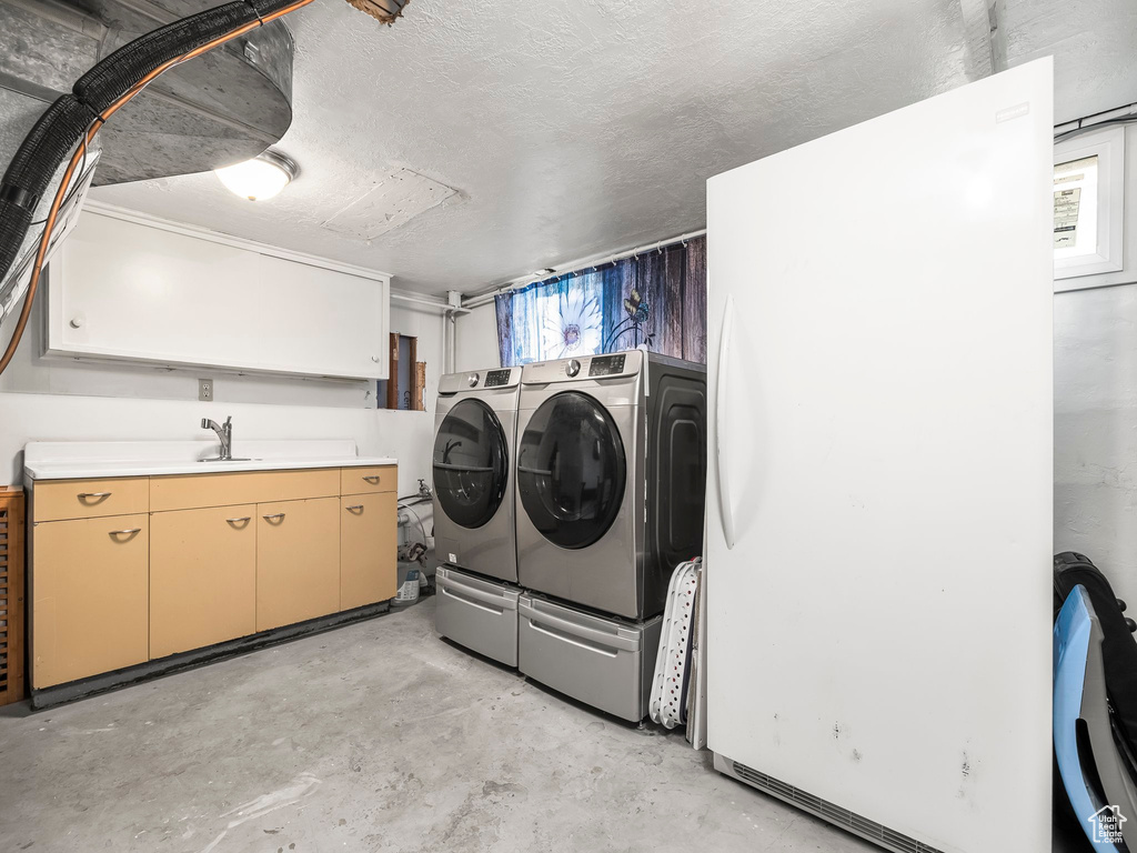 Washroom with separate washer and dryer, cabinet space, and a textured ceiling