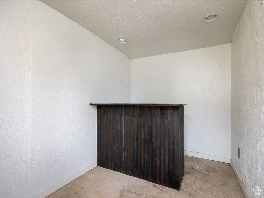 Unfurnished room featuring a dry bar, recessed lighting, and concrete flooring