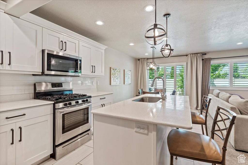 Kitchen with stainless steel appliances, recessed lighting, a textured ceiling, light countertops, and tasteful backsplash