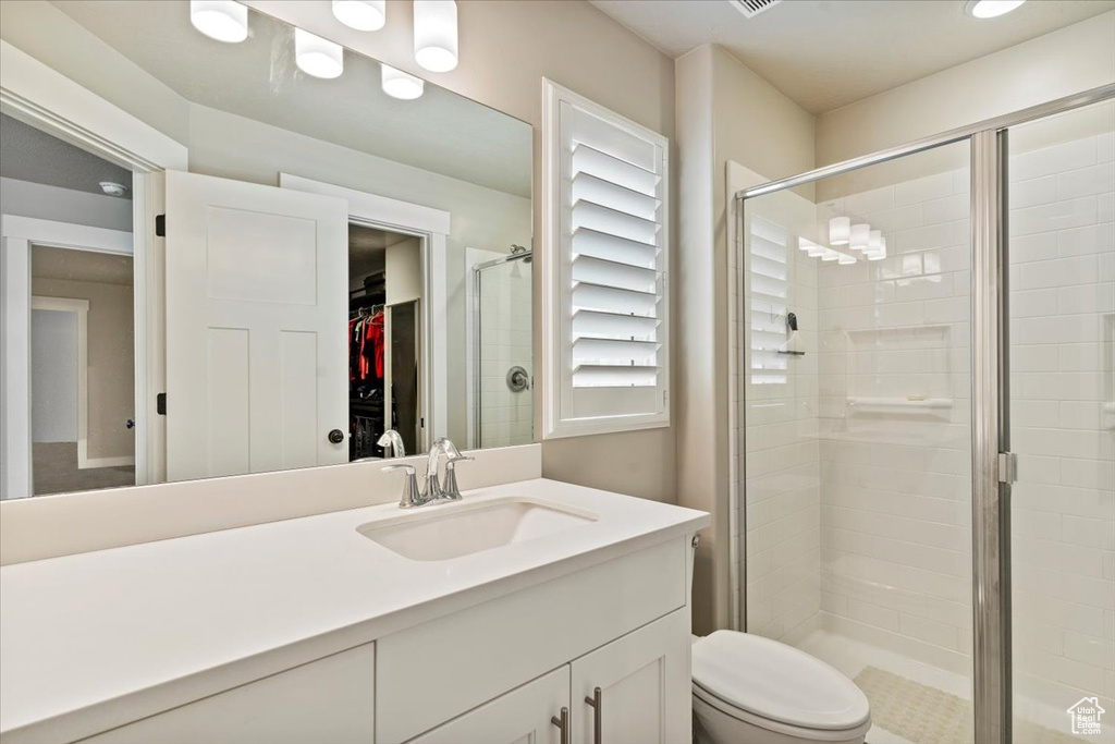 Bathroom featuring vanity, a stall shower, and a walk in closet