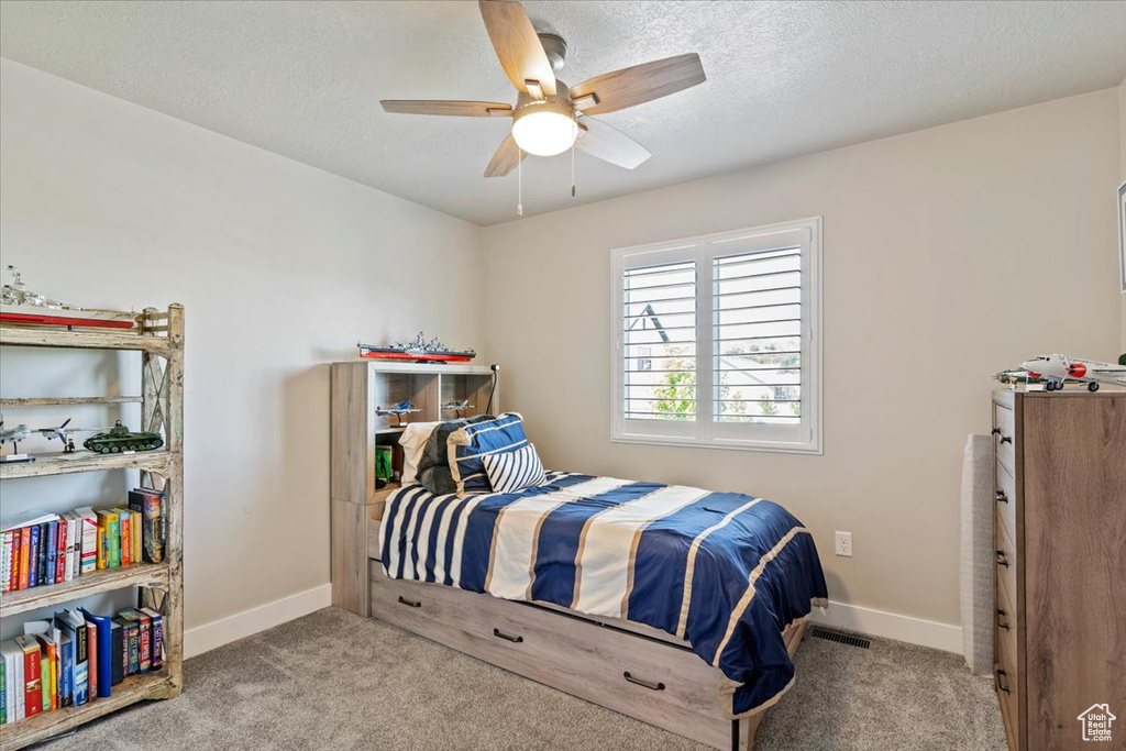 Carpeted bedroom with a textured ceiling and a ceiling fan