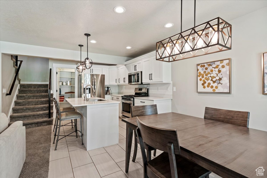Kitchen with appliances with stainless steel finishes, white cabinets, a kitchen breakfast bar, light countertops, and recessed lighting